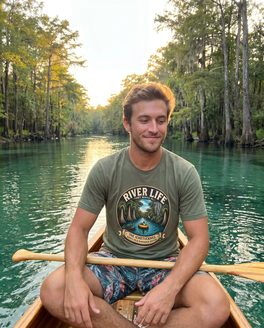 River Life Mens Tee — man in canoe on teal spring river, golden backlight, cypress corridor